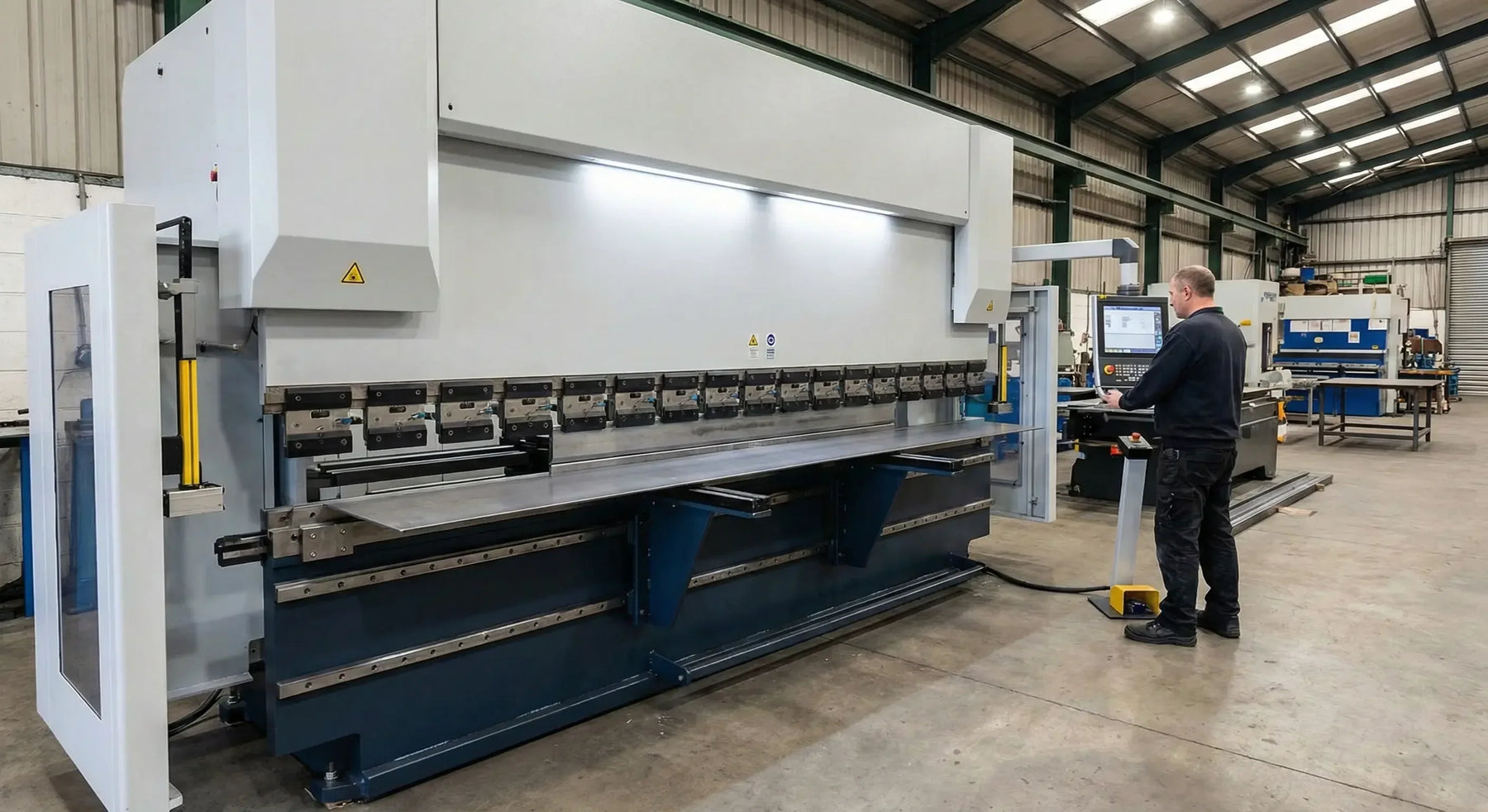 Prensa plegadora CNC de gran formato doblando una lámina de 3 metros de largo, destacando la rectitud perfecta del doblez gracias al sistema de compensación de deflexión.